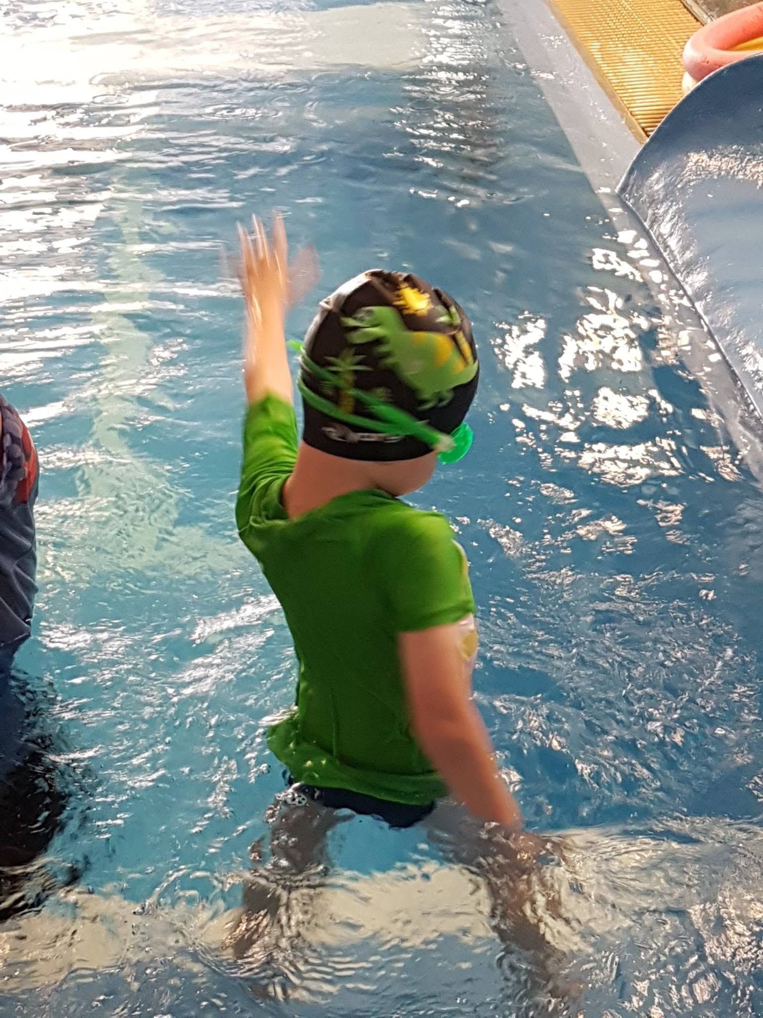 Child in a Green Swim Cap and Shirt Stands in a Pool — Swim Care Boambee in Coffs Harbour, NSW