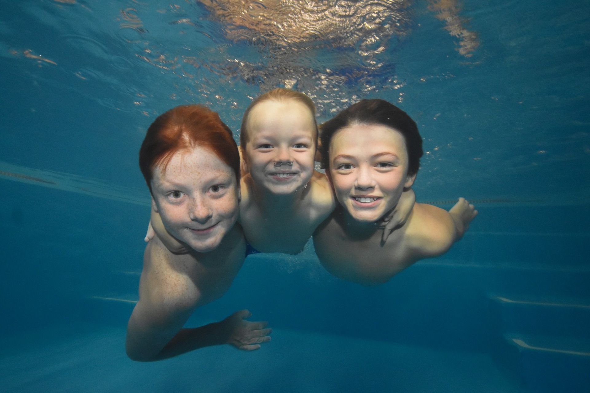Three children are underwater in a swimming pool— Swim Care Boambee in Coffs Harbour, NSW