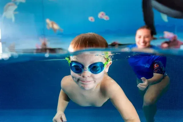 Two Ladies in Pool One Wearing Neon Pink Cap Holding Up Foot — Swim Care Boambee in Coffs Harbour, NSW