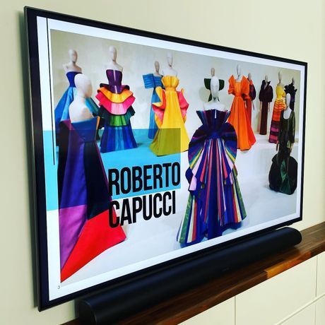 TV screen showing Roberto Capucci fashion designs and colorful dresses on mannequins