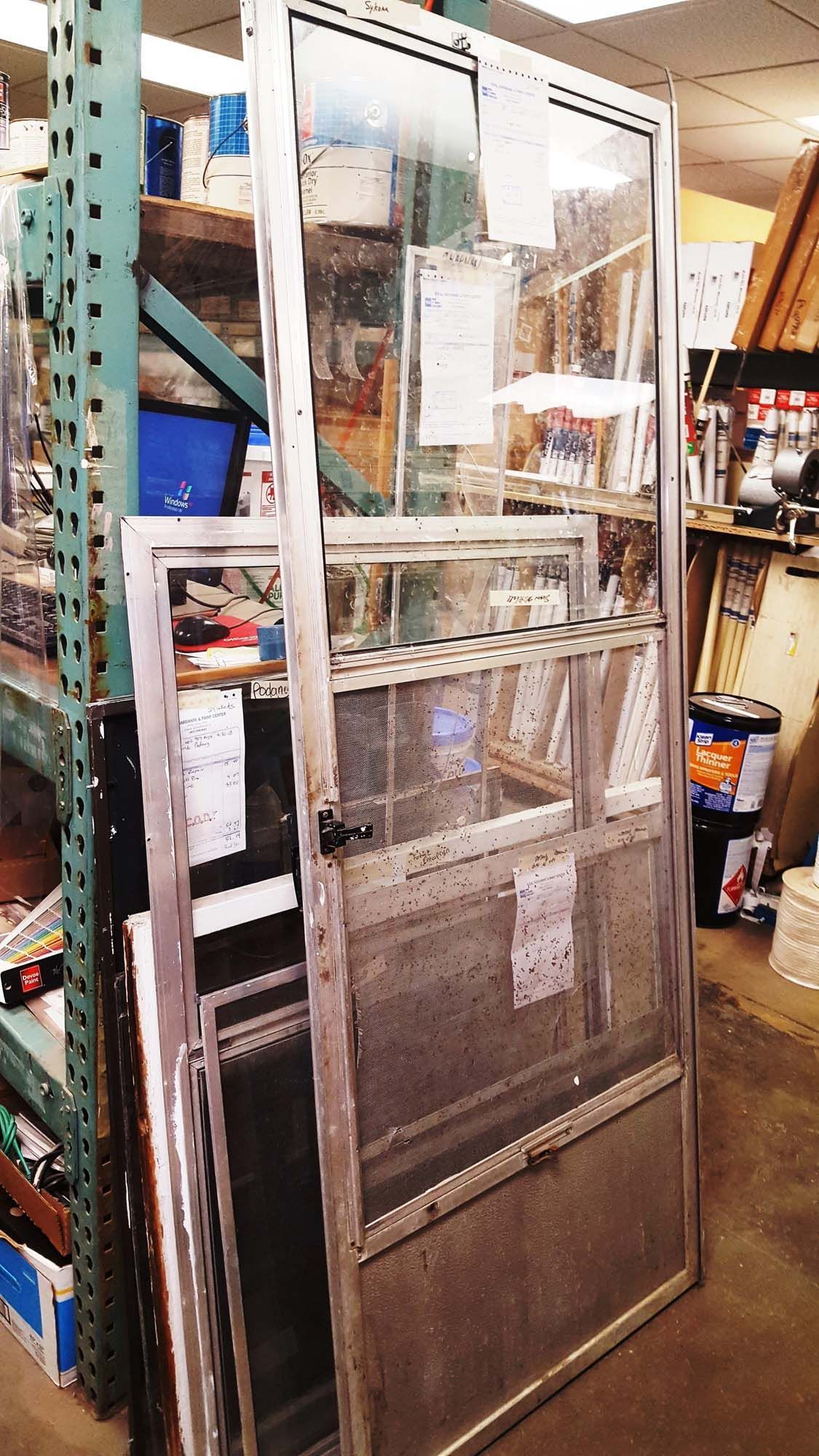 A screen door is sitting in a warehouse next to a shelf.