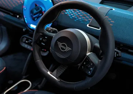 Close-up of a custom black racing steering wheel and dashboard with blue accents inside a car interior