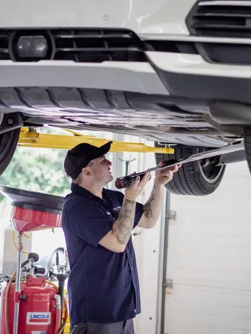 Mechanic inspecting the underside of a car on a lift in a garage