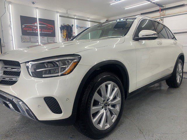 A white mercedes benz glc 300 is parked in a garage.