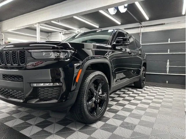 A black jeep is parked in a garage on a checkered floor.