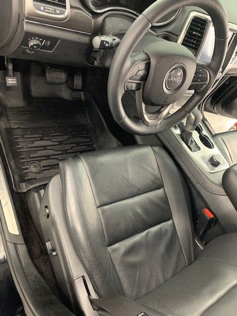 The interior of a jeep grand cherokee with leather seats and a steering wheel.