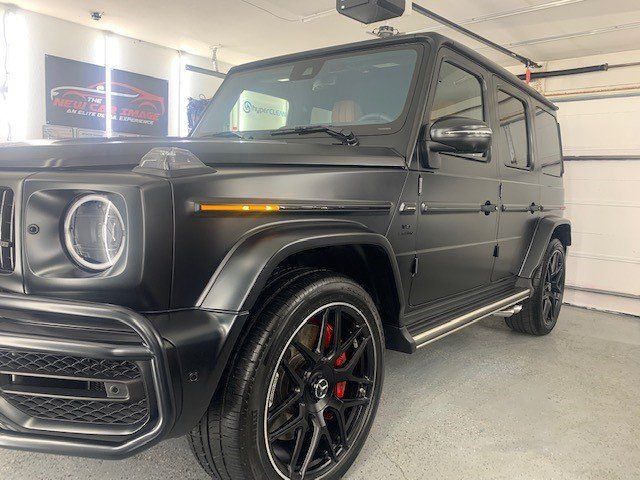 A black mercedes benz g63 amg is parked in a garage.