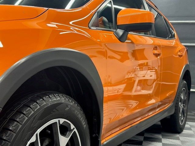 A close up of an orange car with a black tire