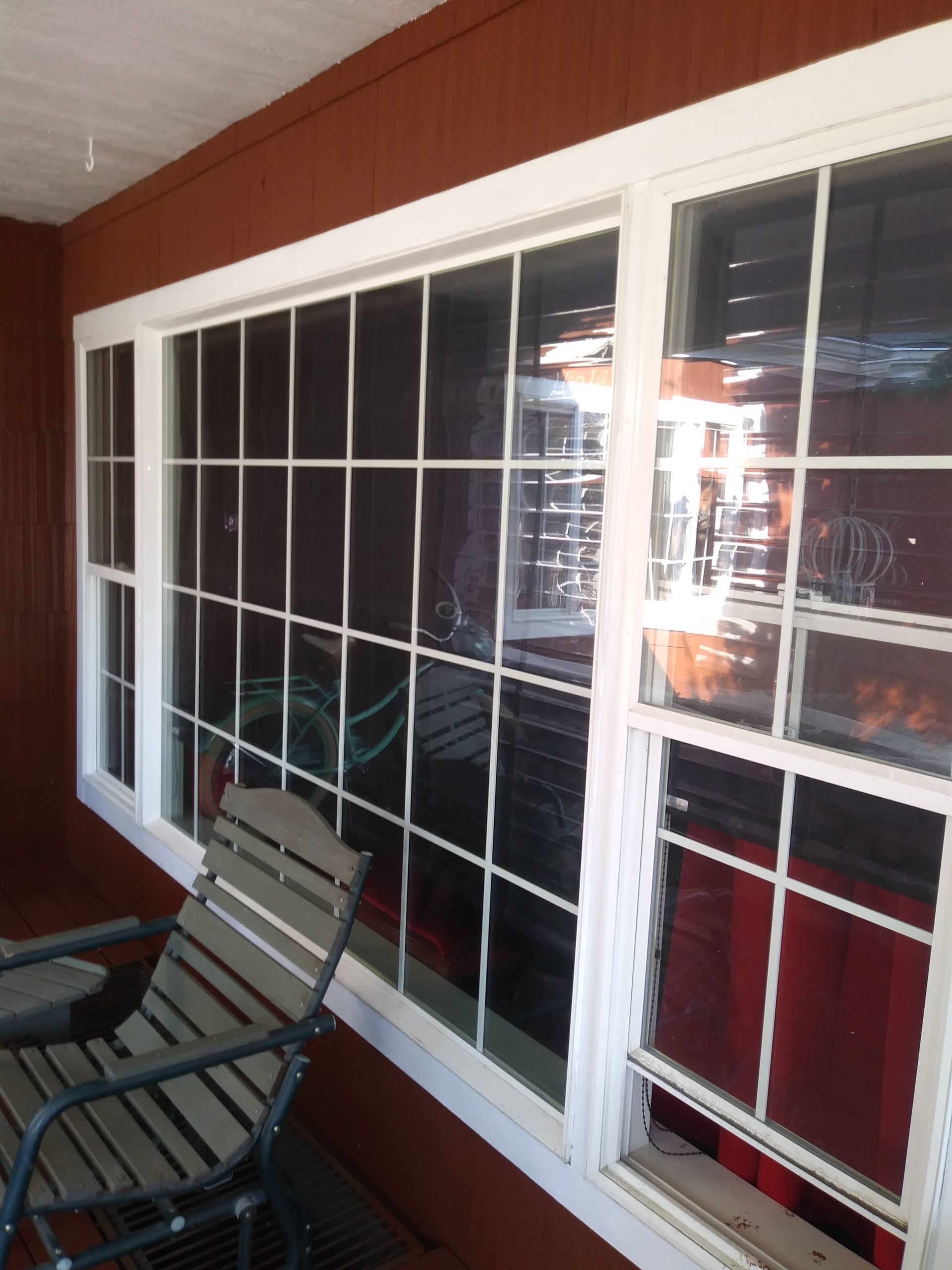Covered patio with white-framed windows, red wall, and two patio chairs.