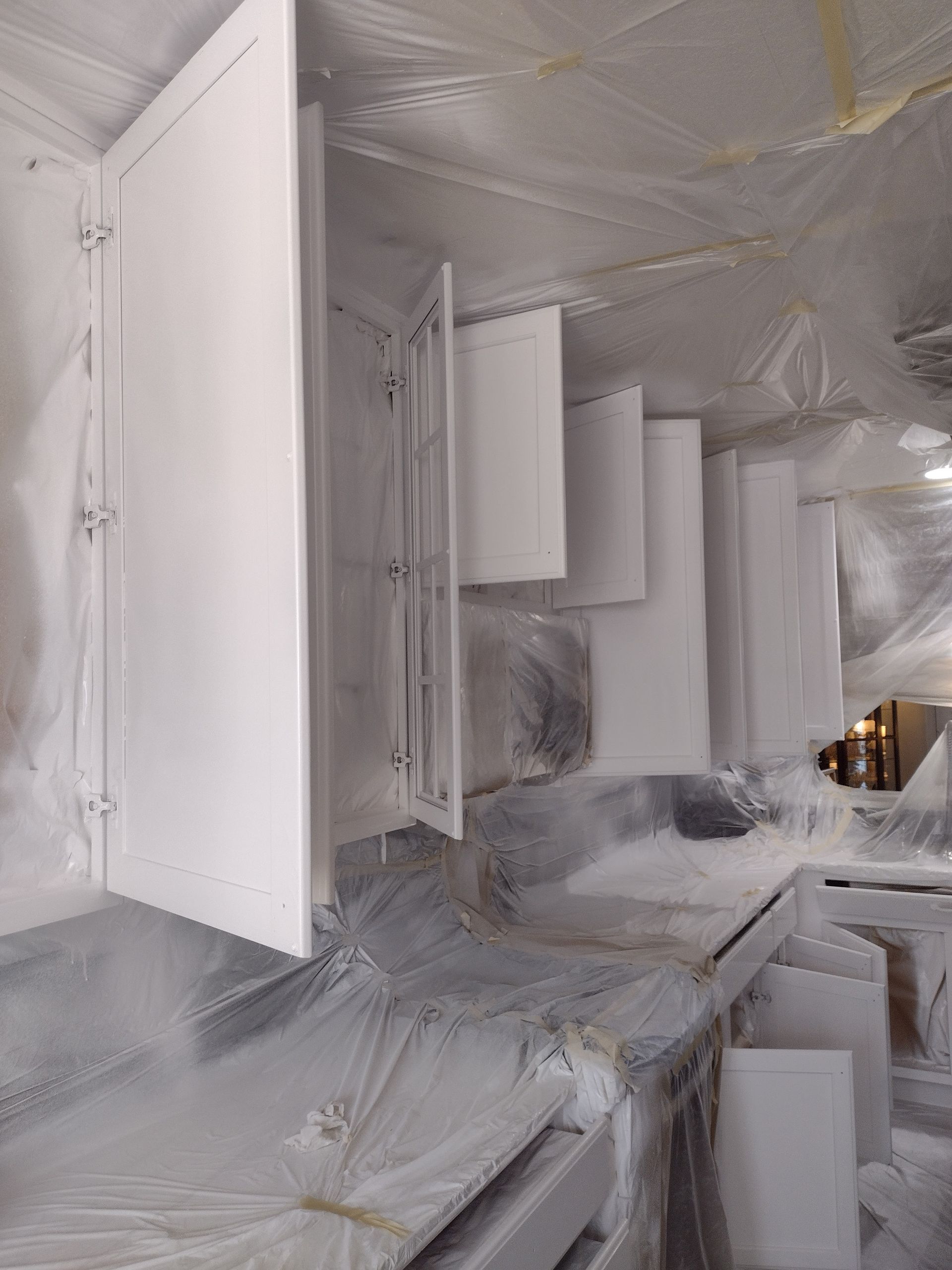 White interior with folding doors and plastic sheeting, resembling a room under renovation or damage recovery.