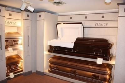 Showroom of stacked dark wood coffins beneath a white coffin display