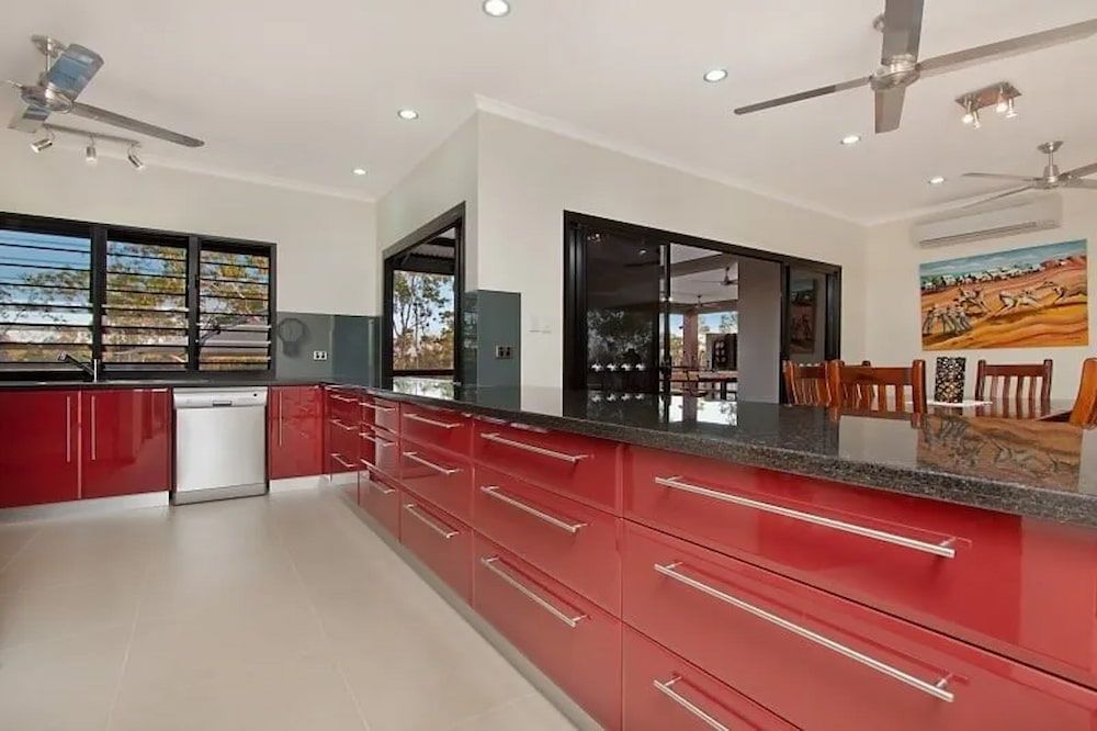 A Kitchen With Red Cabinets and Granite Counter Tops — Custom Cabinets Design in Berrimah, NT