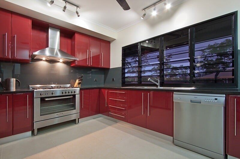 A Kitchen with Red Cabinets and Stainless Steel Appliances — Custom Cabinets Design in Berrimah, NT
