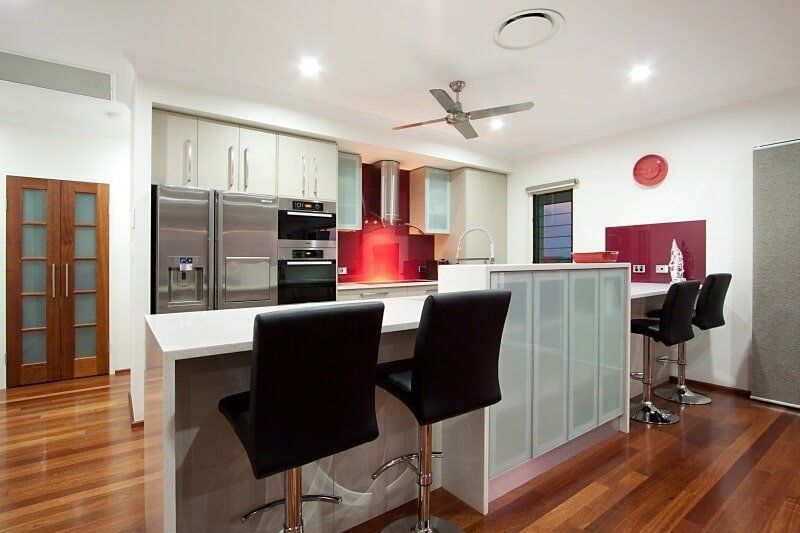 A Kitchen with Stools and A Ceiling Fan — Custom Cabinets Design in Berrimah, NT