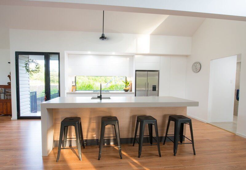 A Kitchen with A Large Island , Stools and A Refrigerator — Custom Cabinets Design in Berrimah, NT