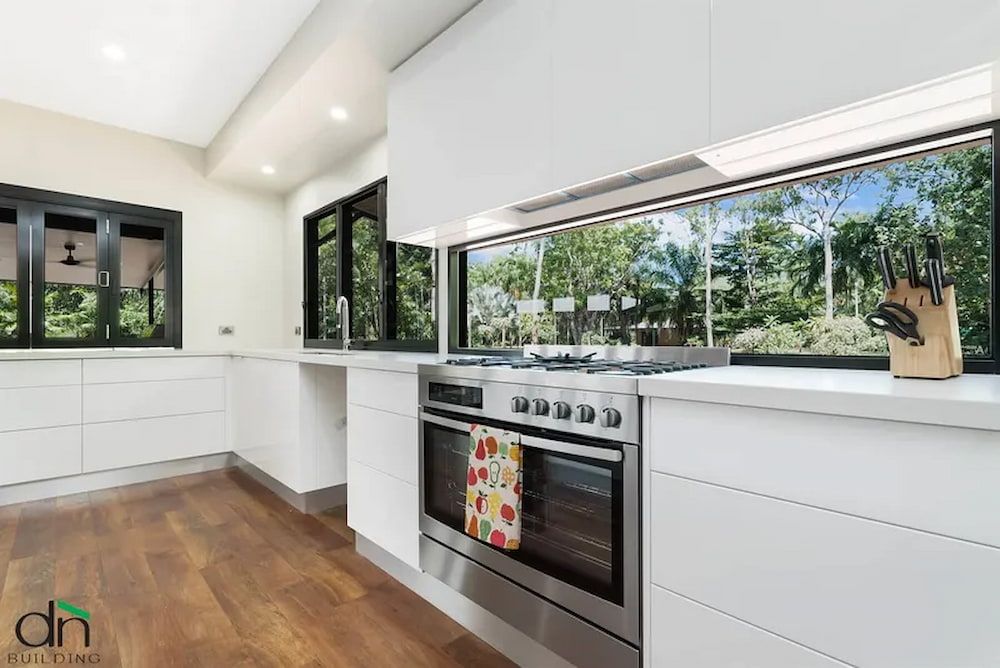 A Kitchen With White Cabinets and Stainless Steel Appliances and a Large Window — Custom Cabinets Design in Berrimah, NT