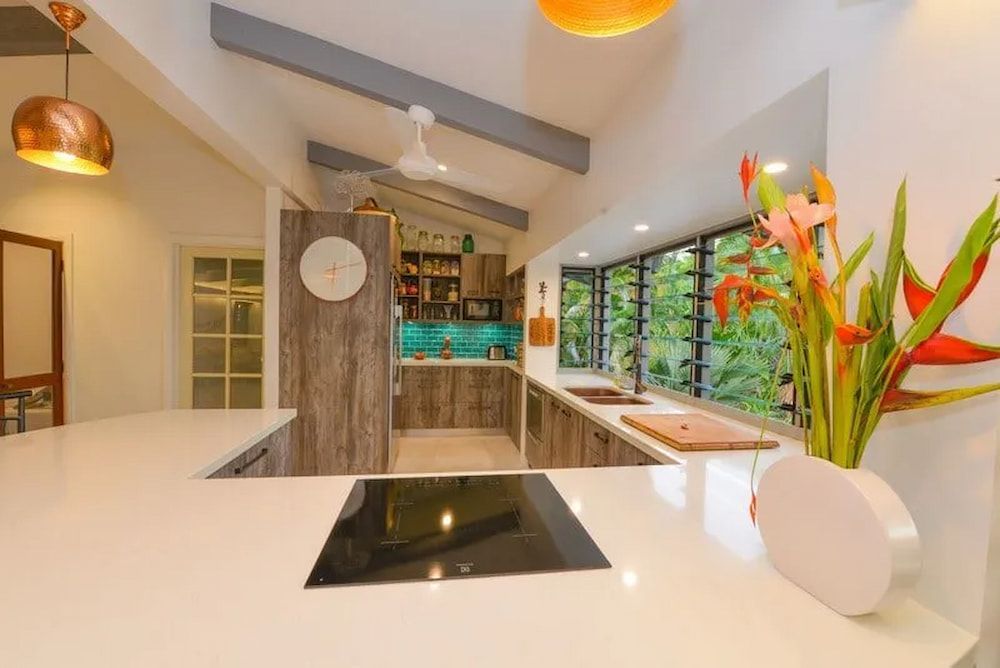 A Kitchen With a Stove Top Oven and a Vase of Flowers on the Counter — Custom Cabinets Design in Berrimah, NT