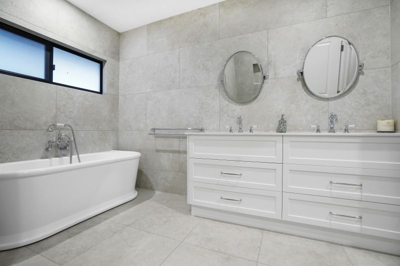 A bathroom with white cabinets, a bath and two circle mirrors — Custom Cabinets Design in Berrimah, NT