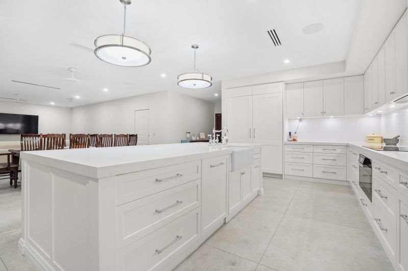 A white kitchen with white cabinets and hanging lights — Custom Cabinets Design in Berrimah, NT