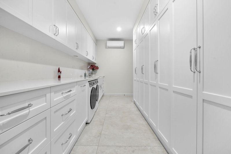 A Laundry Room With White Cabinets and a Washer and Dryer — Custom Cabinets Design in Berrimah, NT