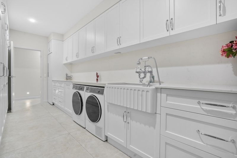 A laundry with White Cabinets and Shelves and A tiled Floor — Custom Cabinets Design in Berrimah, NT