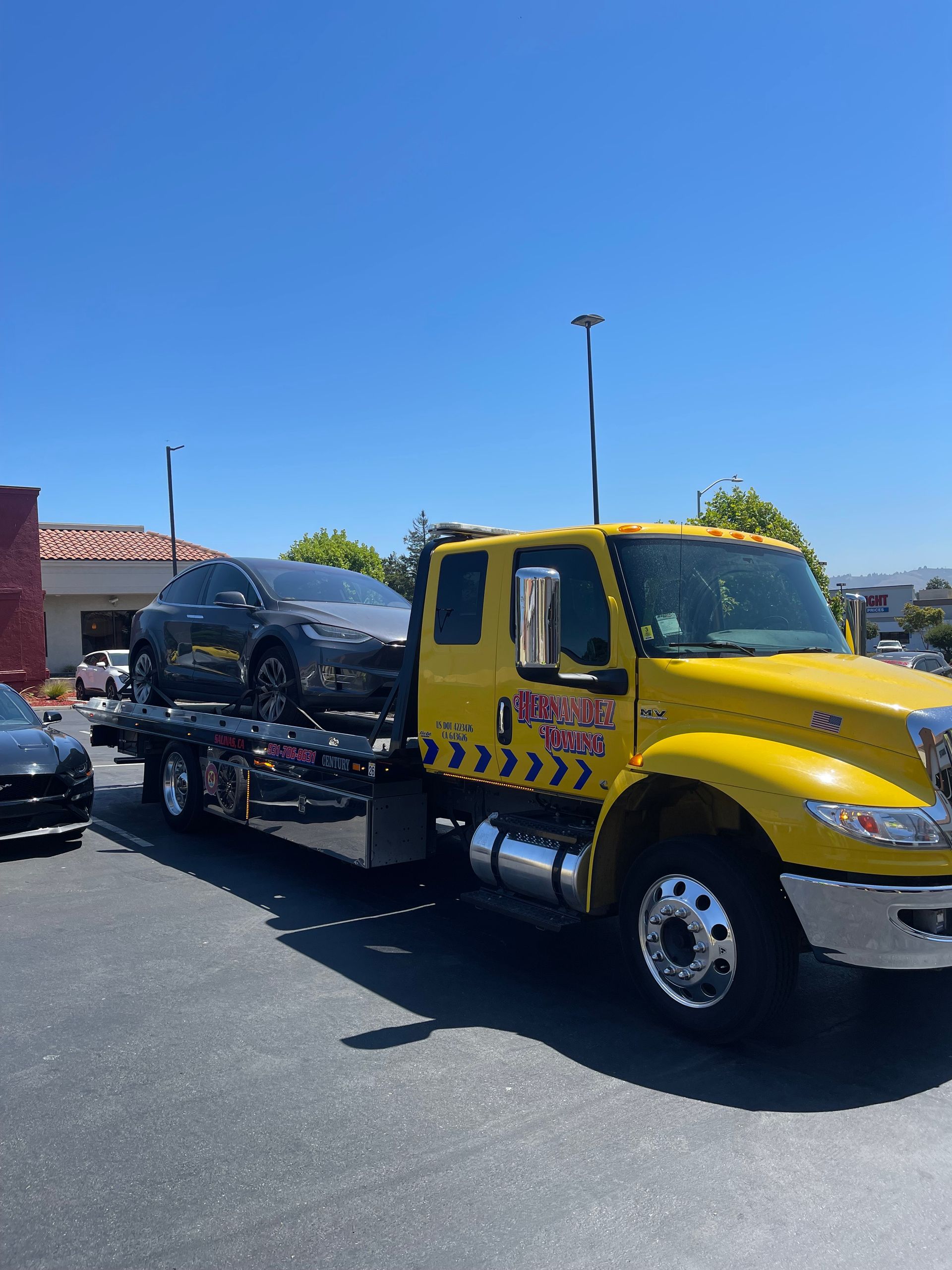 Yellow tow truck carrying a gray car on a sunny day. Yellow tow truck carrying a gray car on a sunny day.