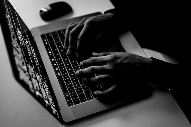 Een persoon typt code op een laptopcomputer