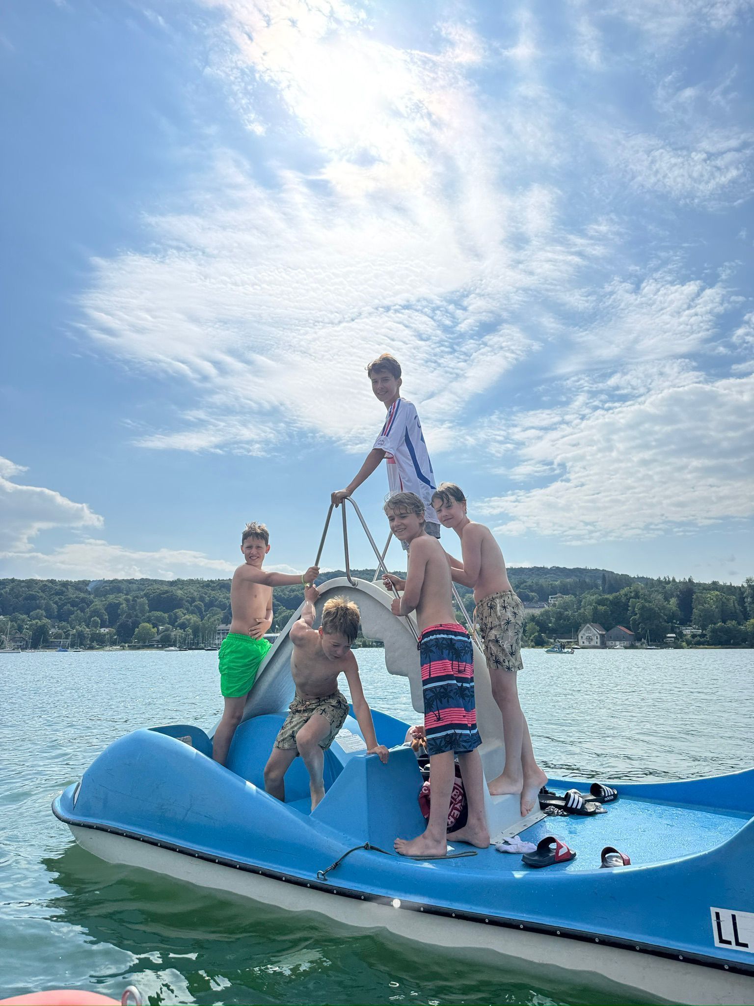 Sechs Personen auf einem blauen Tretboot auf dem Wasser an einem sonnigen Tag.