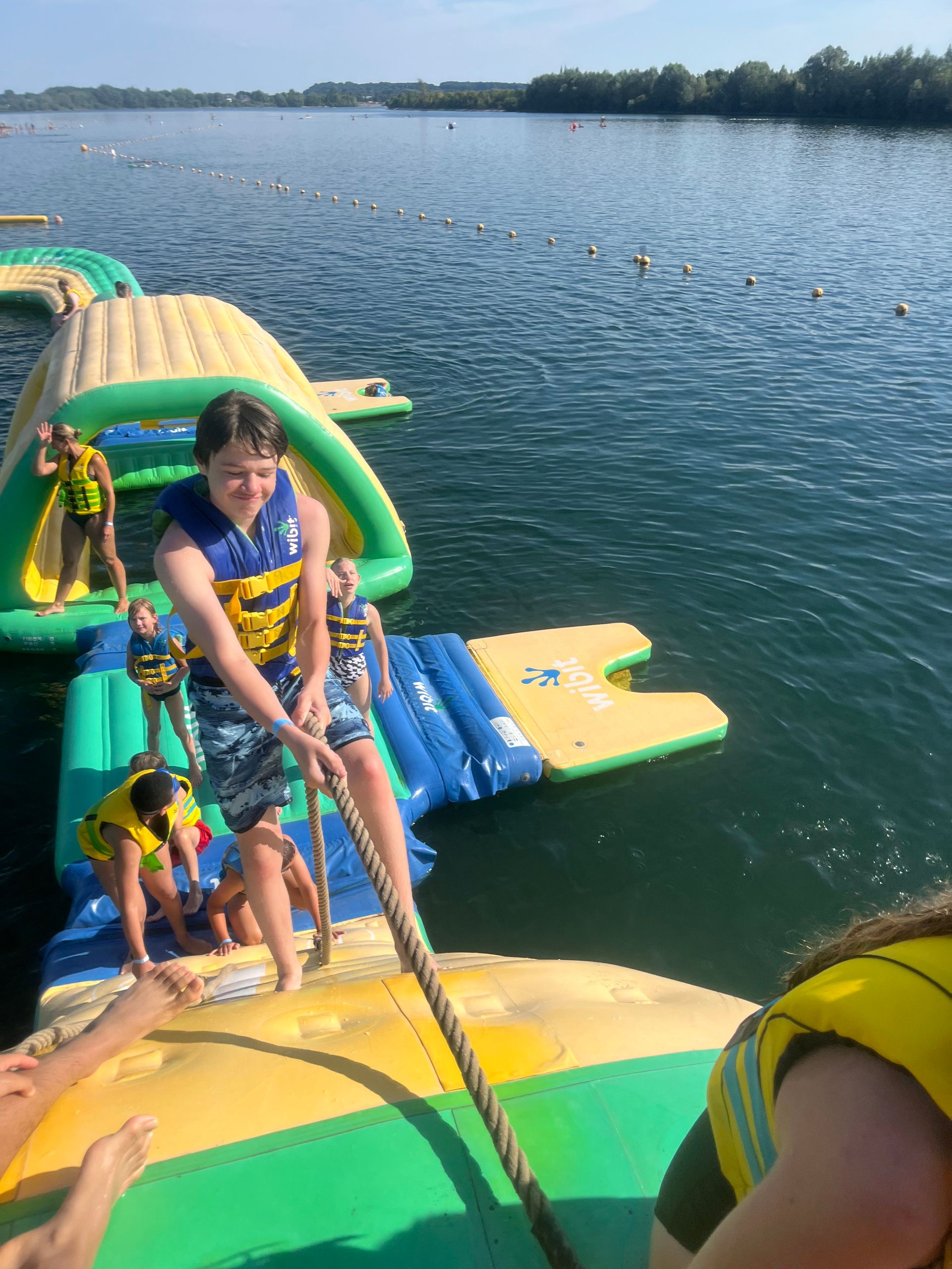 Menschen auf einem aufblasbaren Hindernisparcours im Wasser; ein Junge zieht an einem Seil.