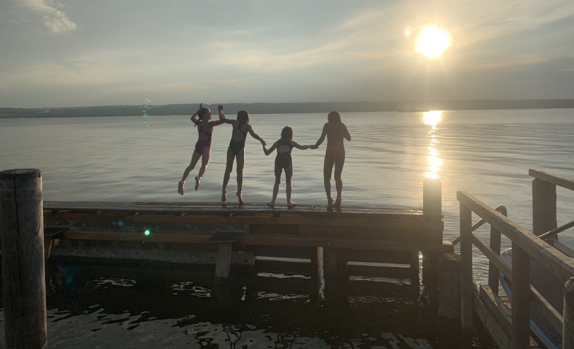 Eine Gruppe von Menschen steht auf einem Dock und hält sich an den Händen.