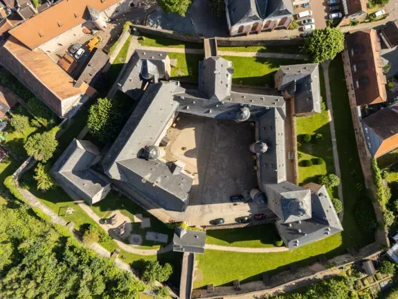 Luftaufnahme einer sternförmigen Festung mit zentralem Innenhof, umgeben von grünen Rasenflächen und Gebäuden.