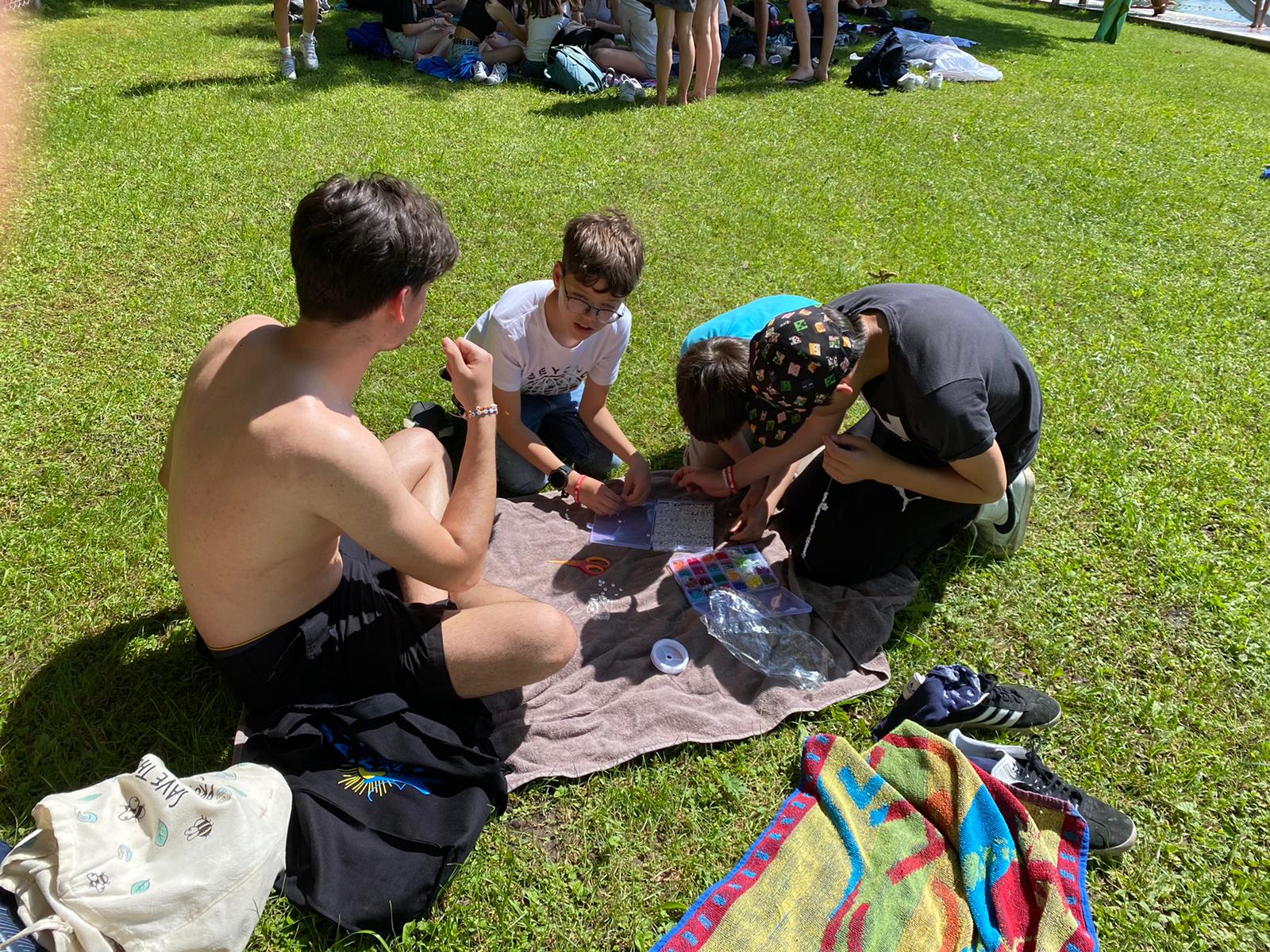 Eine Gruppe von Menschen sitzt im Gras und schaut auf eine Karte.