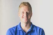 Ein Mann im blauen Poloshirt lächelt in die Kamera.