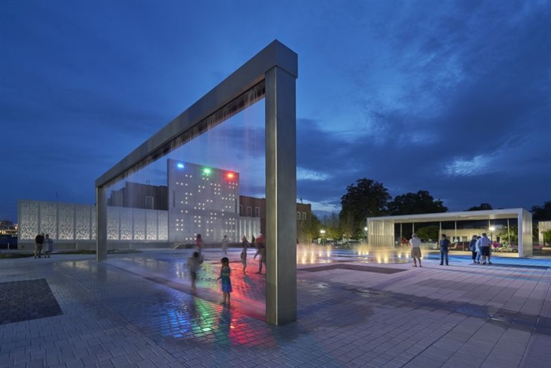 A group of people are playing in a fountain at night