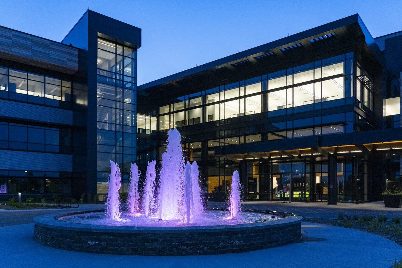 A large building with a fountain in front of it at night.