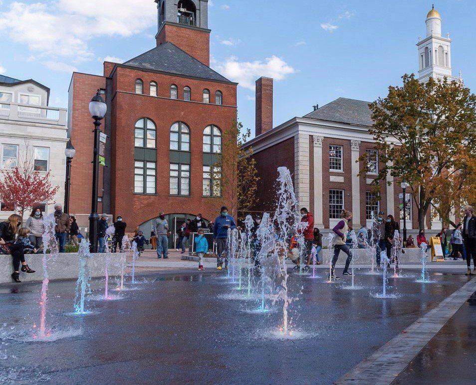 People are playing in a fountain in front of a brick building