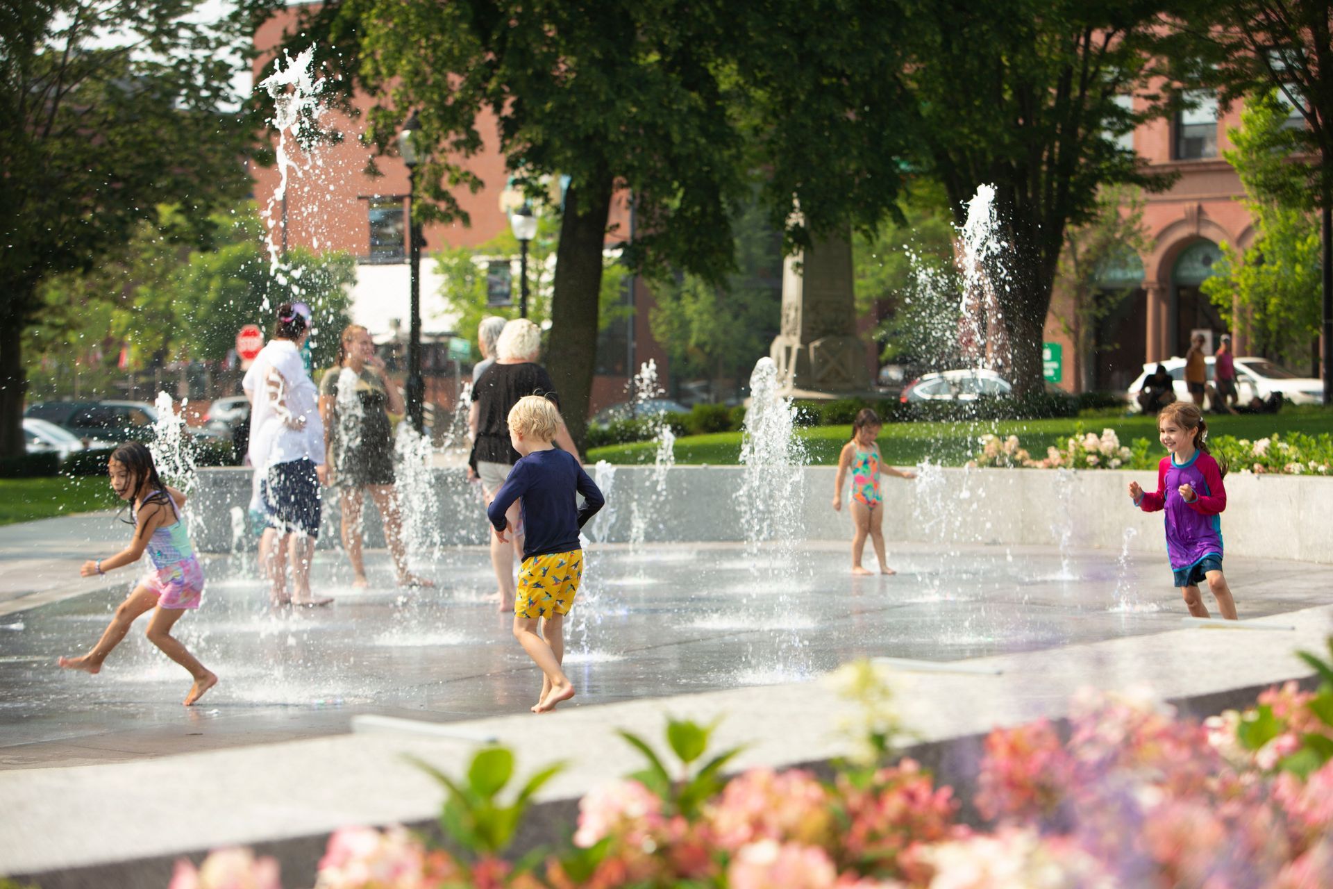 A group of children are playing in a fountain in a park.