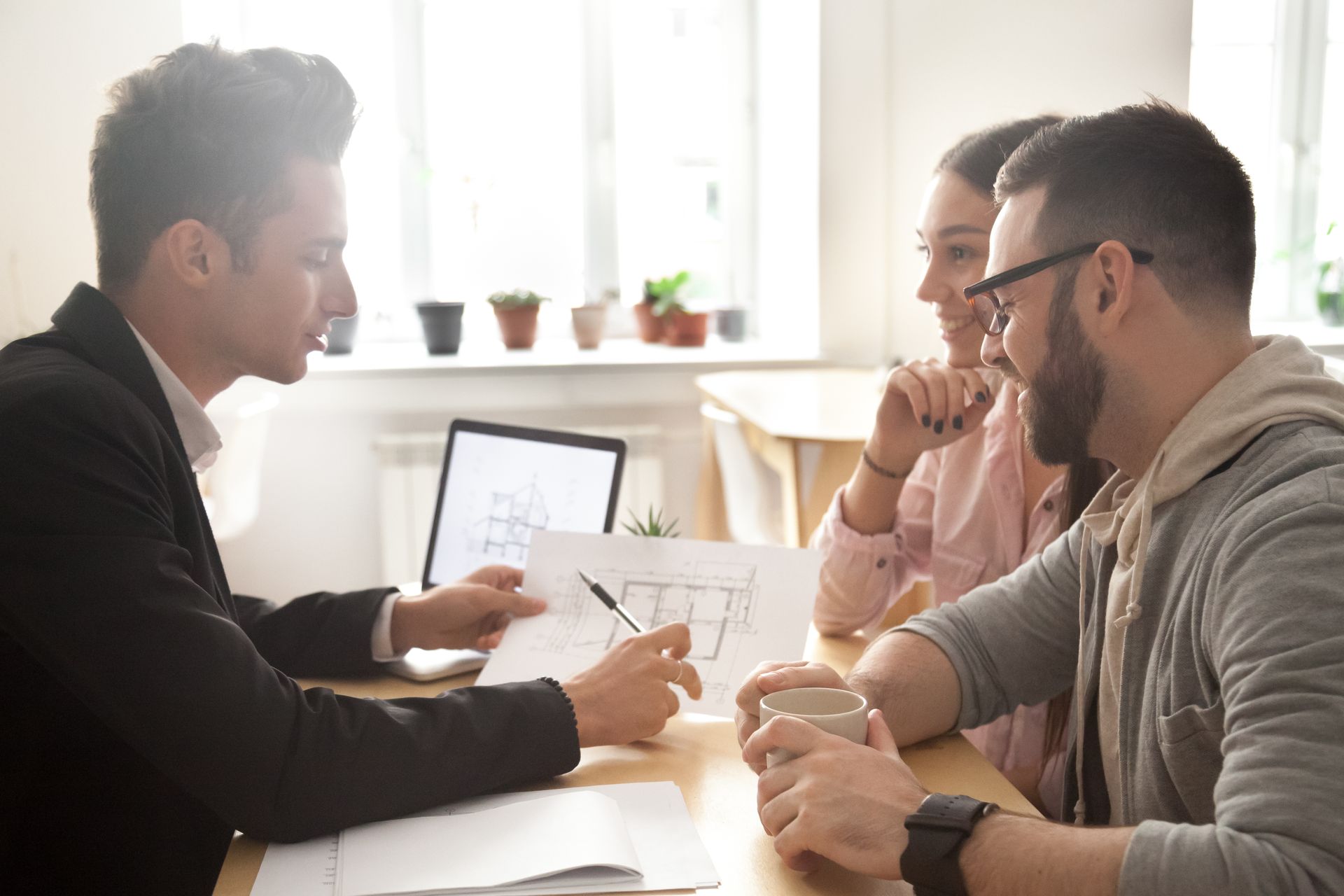 Three people in a bright office discussing documents at a table