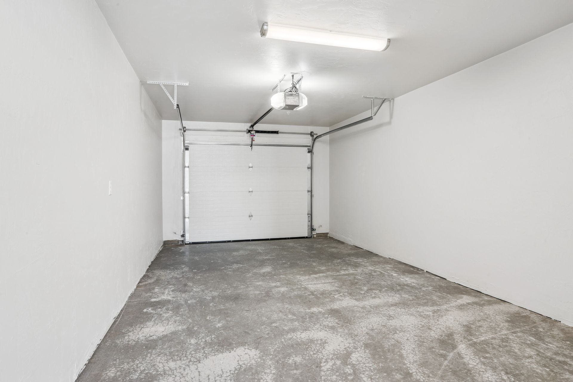 Empty white garage with closed door and gray concrete floor