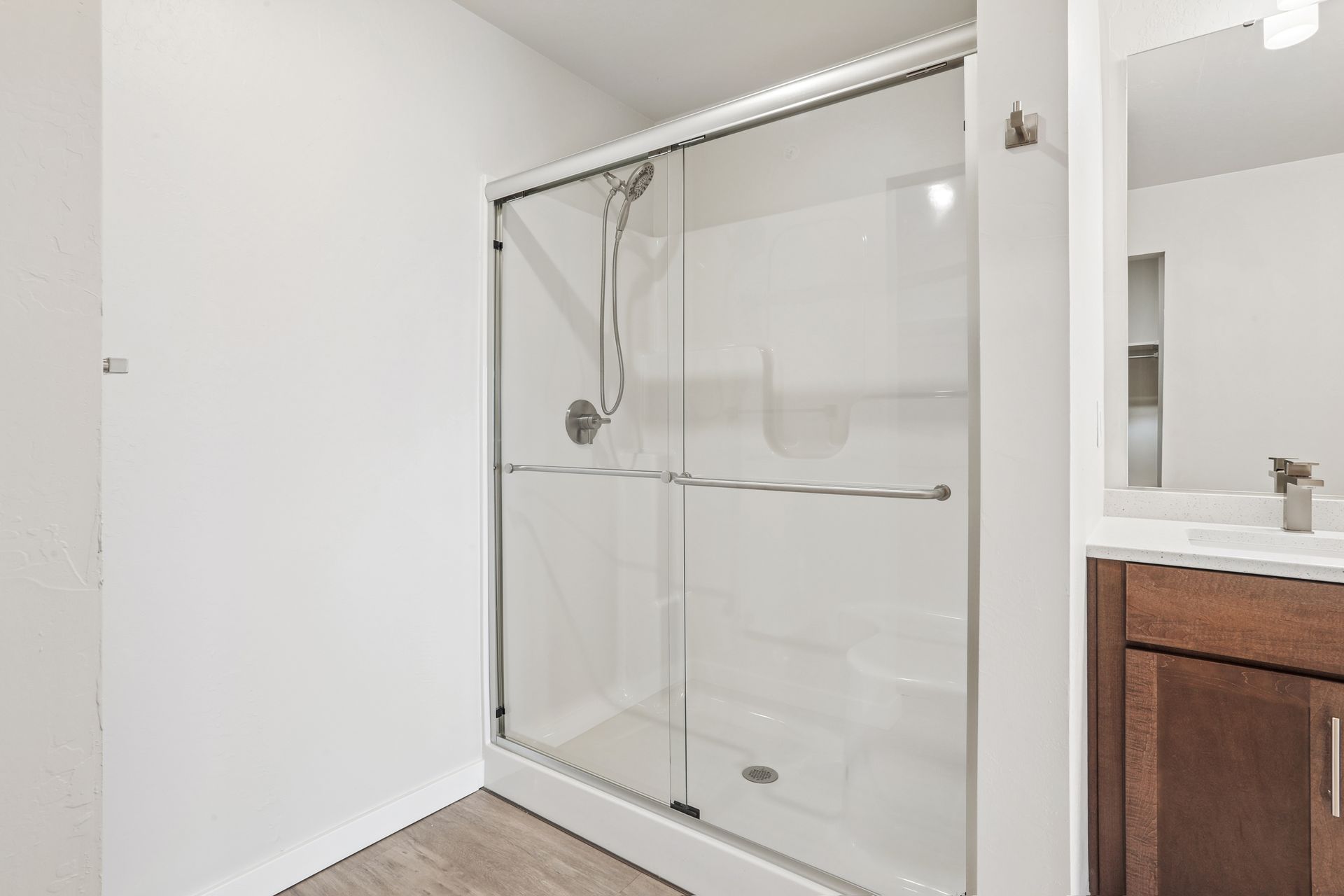 Glass shower enclosure with chrome grab bar in a bright bathroom