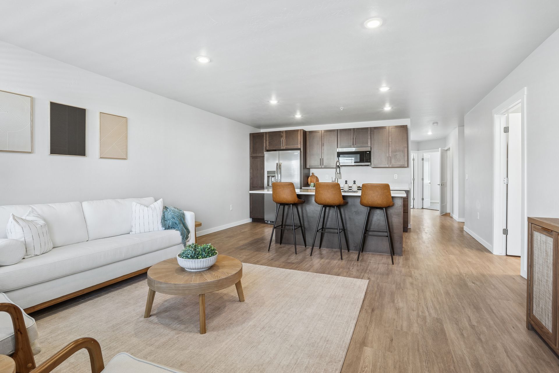 Bright open living room with white sofa, coffee table, and bar stools facing a kitchen island.