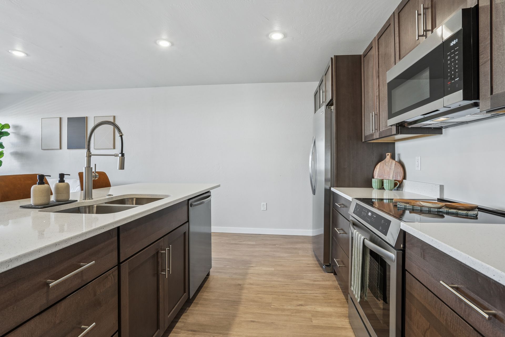 Modern kitchen with dark wood cabinets, large island, stainless steel appliances, and light wood floors