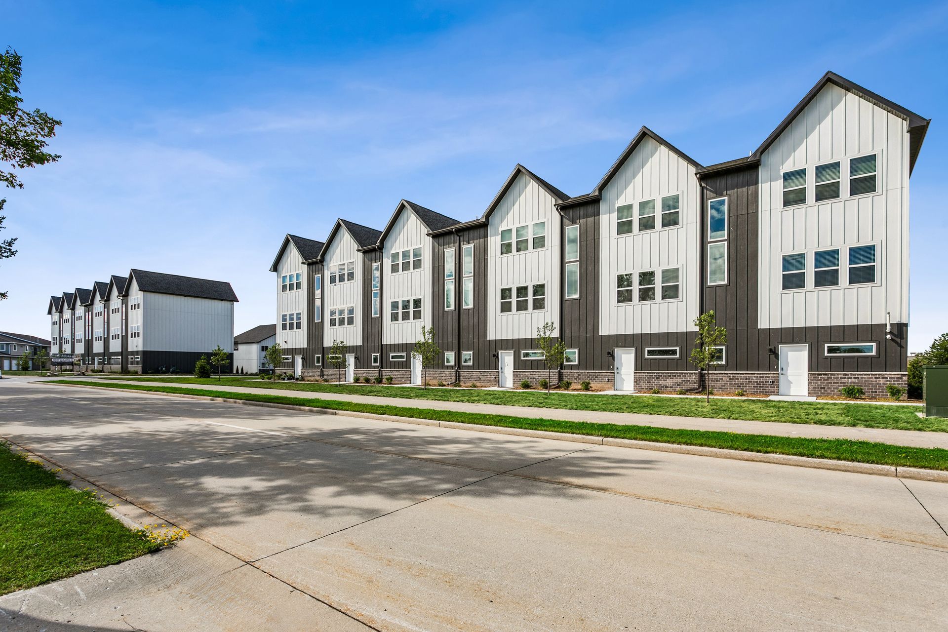 Modern apartment buildings along a quiet street under a blue sky