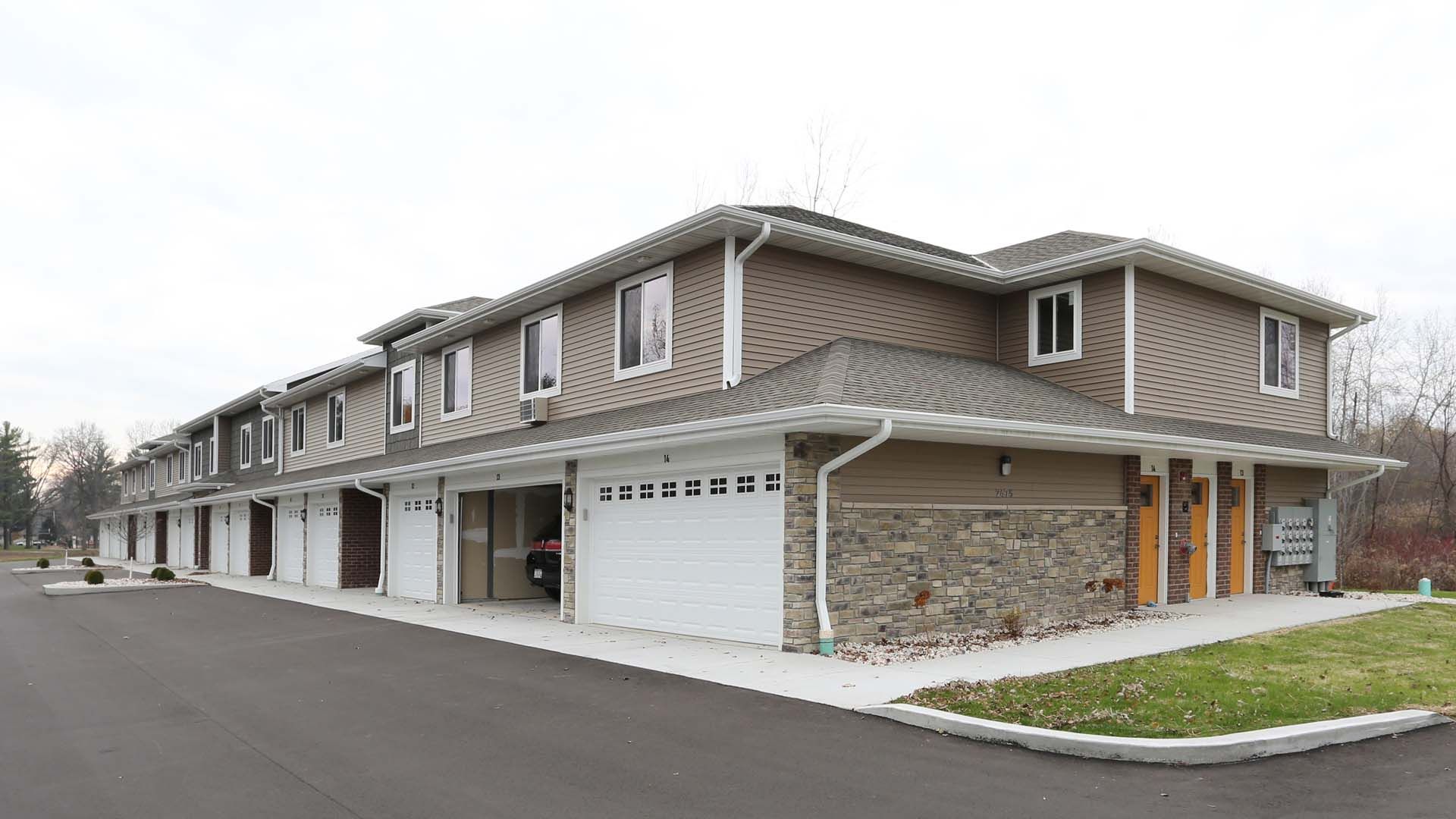 Row of modern townhouses with garages and stone accents along a quiet street
