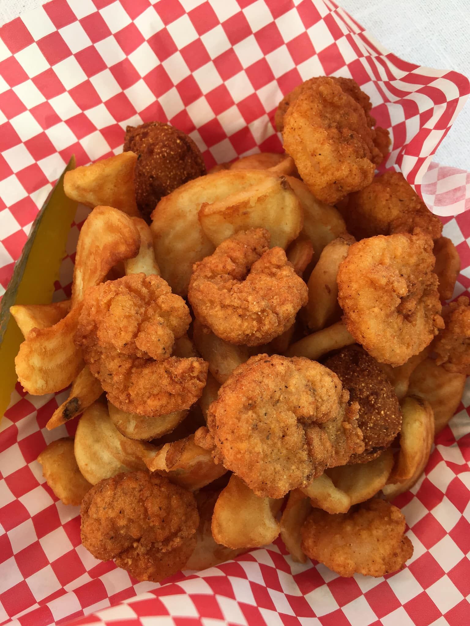 Basket of fried shrimp and French fries in red-and-white checkered paper.