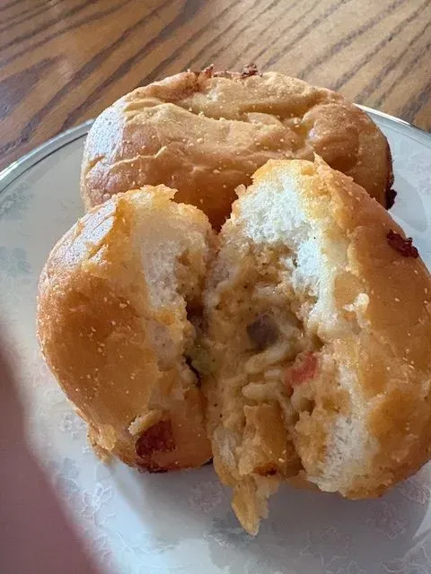 Partially eaten glazed pastry with a crumb filling on a white plate