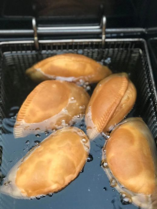 Five shellfish cooking in a metal mesh basket with bubbling oil or water.