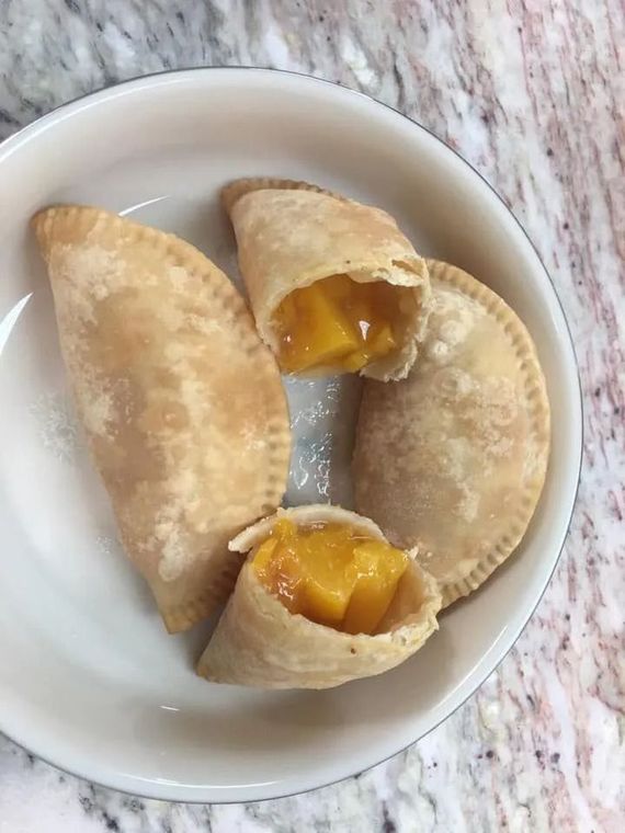 Three pastries on a white plate, two filled with yellow fruit