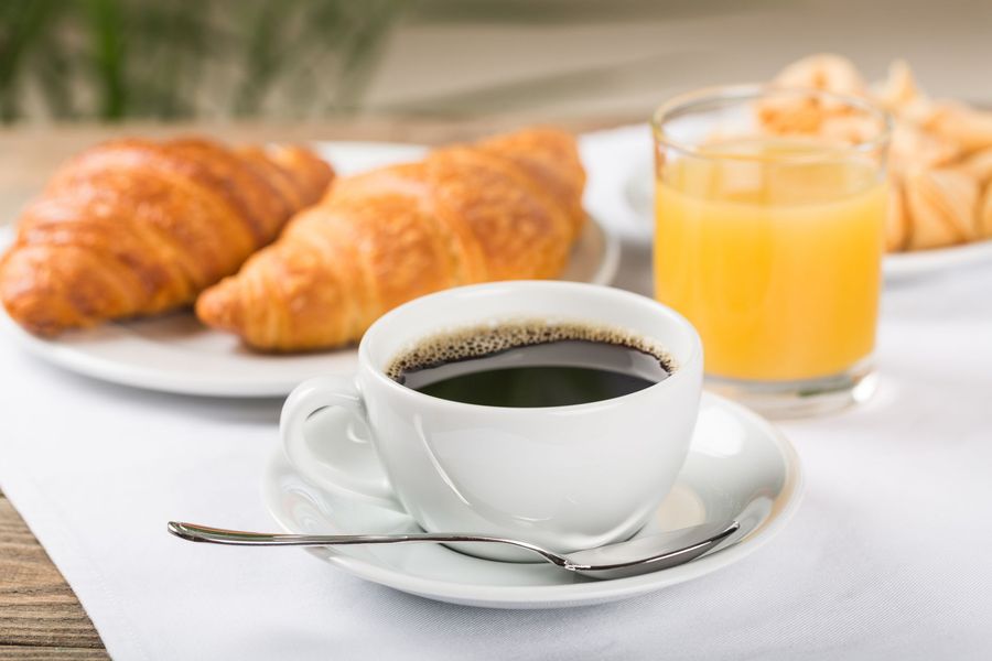 There is a cup of coffee and a glass of orange juice on the table.