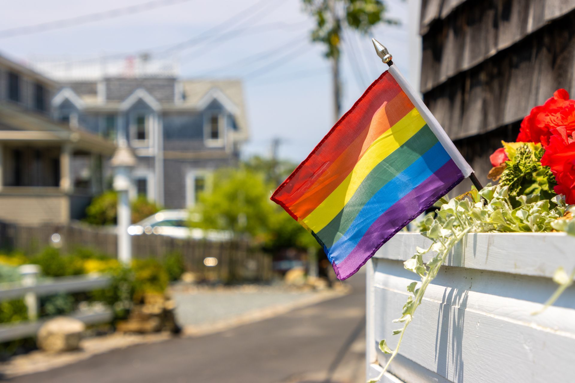 A small rainbow flag is hanging from a white planter.
